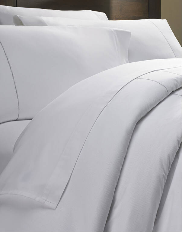 Neatly made bed with Marriott Hotels bedding
